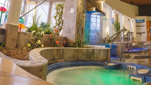 A hot tub area with multiple tubs, a wooden bench, and a staircase leading to a higher level. - Le Montagnais (Saguenay)