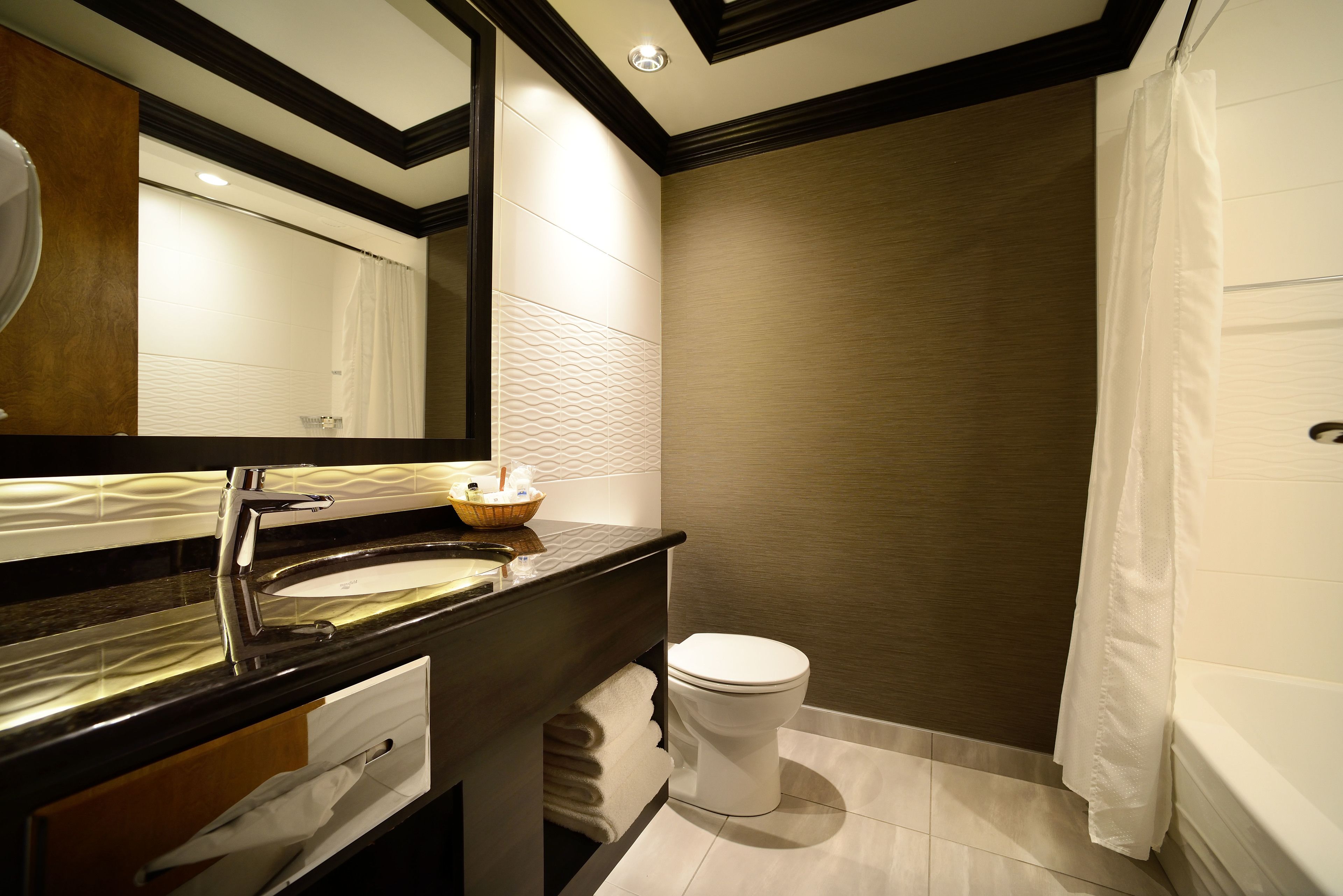 A modern bathroom with a dark countertop, a white sink, and a toilet.