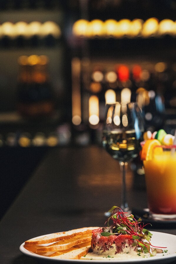 Un bar con un plato de comida, una copa de vino y una bebida de frutas.