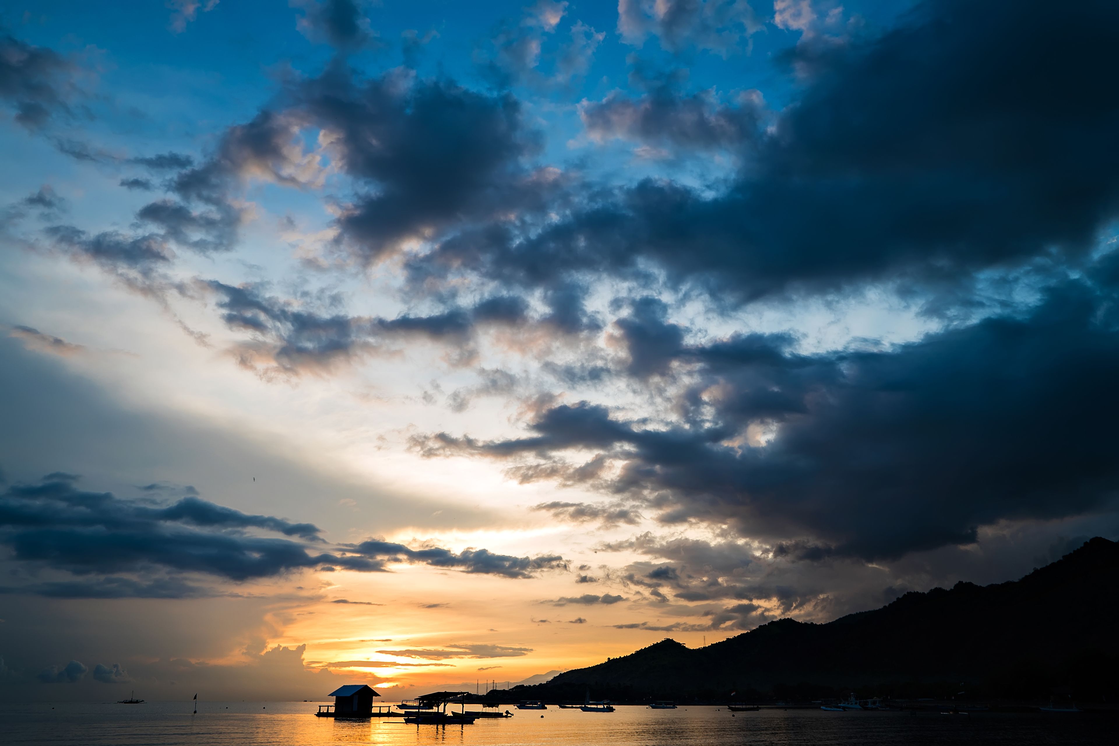 A coastal sunset with boats and a dock.