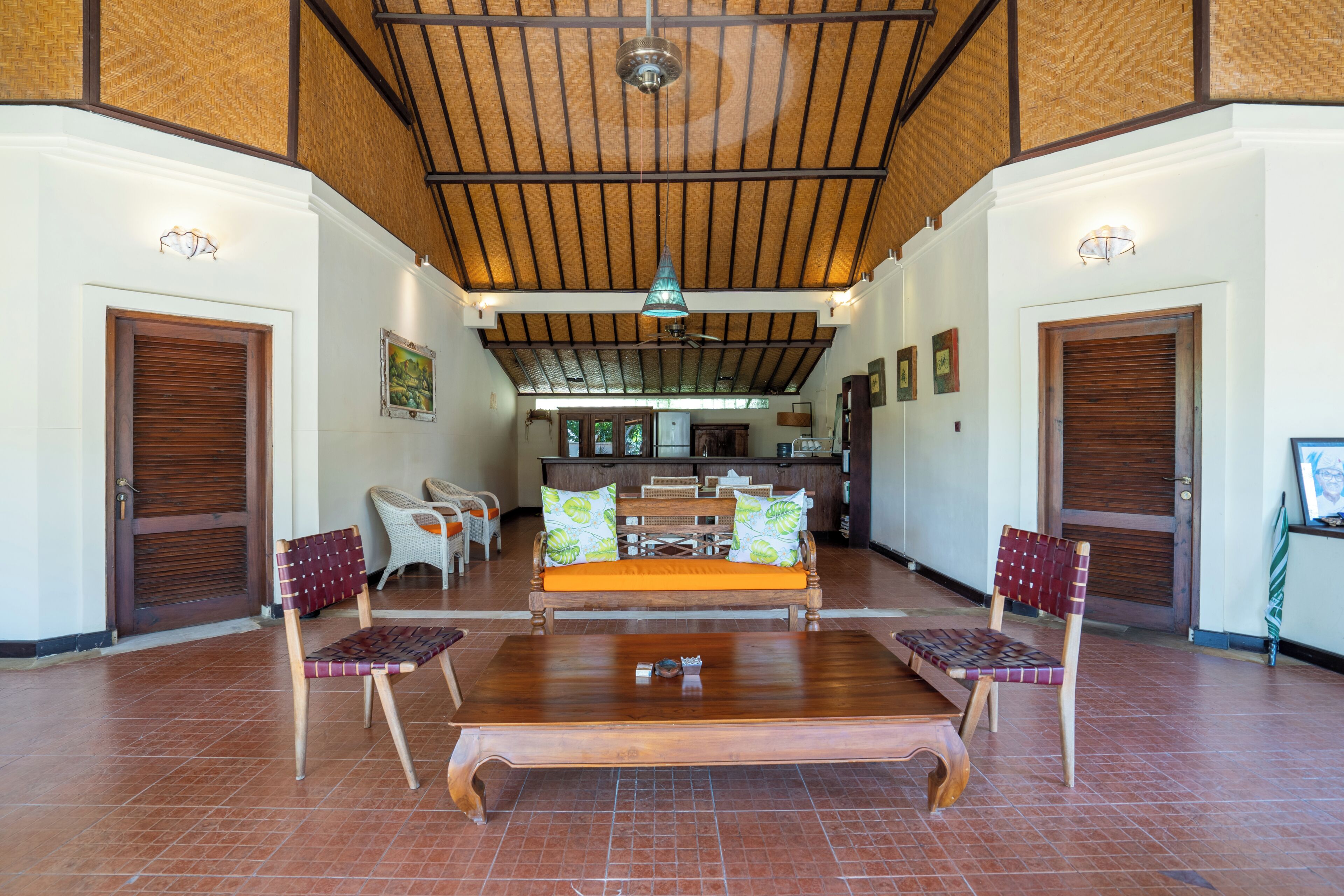 A spacious living area with a wooden ceiling, a sofa set, and two chairs.