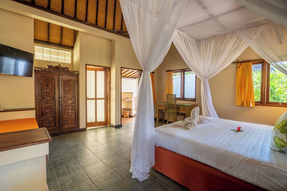 A hotel room with a bed, a desk, a TV, and a wardrobe.