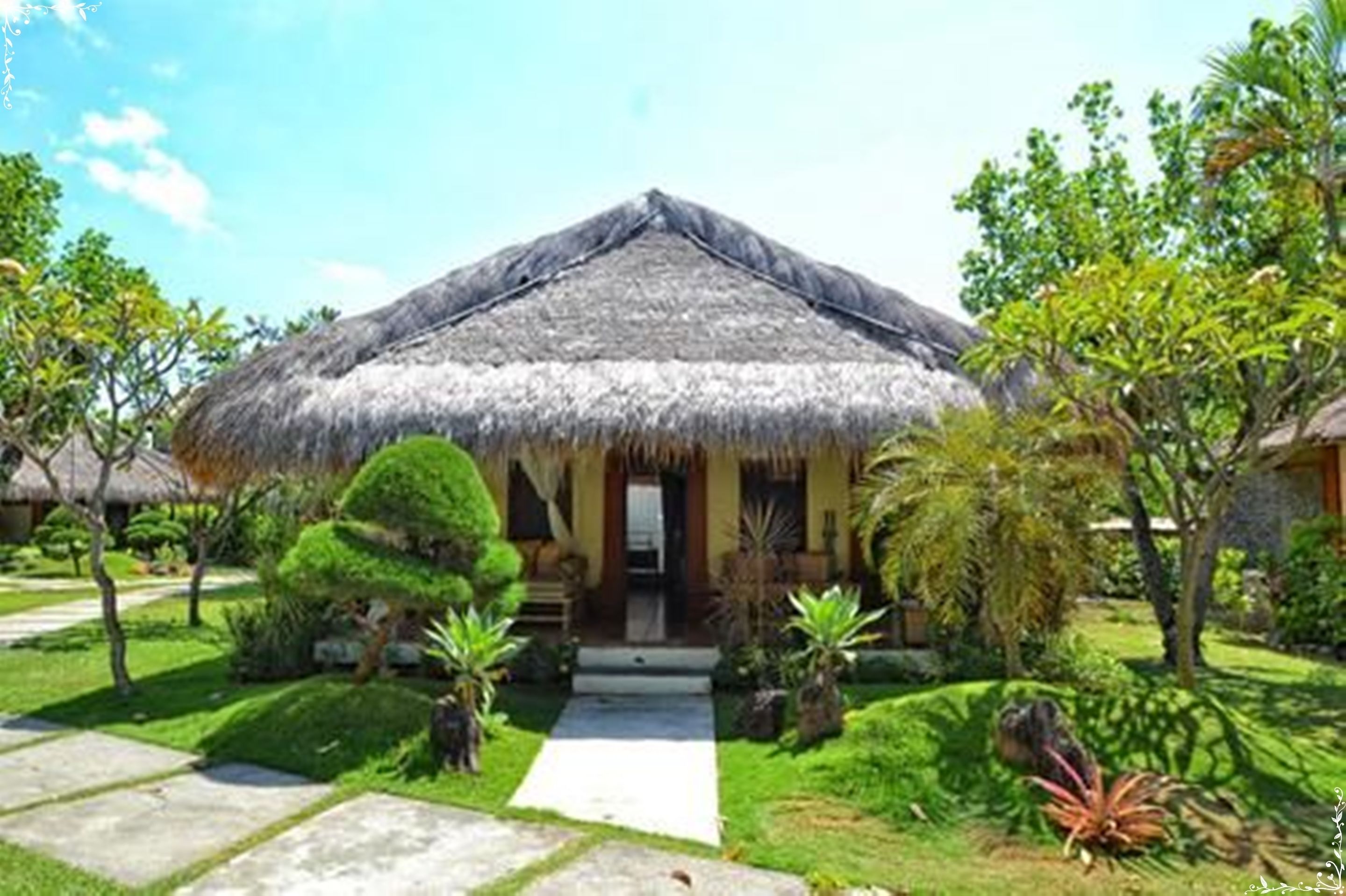 A thatched-roof bungalow with a well-maintained garden and a clear pathway leading to the entrance.