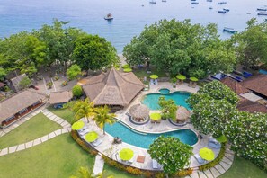 A resort with a central swimming pool, lounge areas, and thatched-roof structures. - Taman Sari Bali Resort & Spa (Pemuteran)