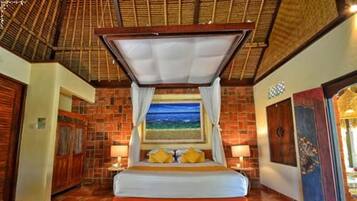 Un dormitorio con cama, un cuadro y vista al mar.