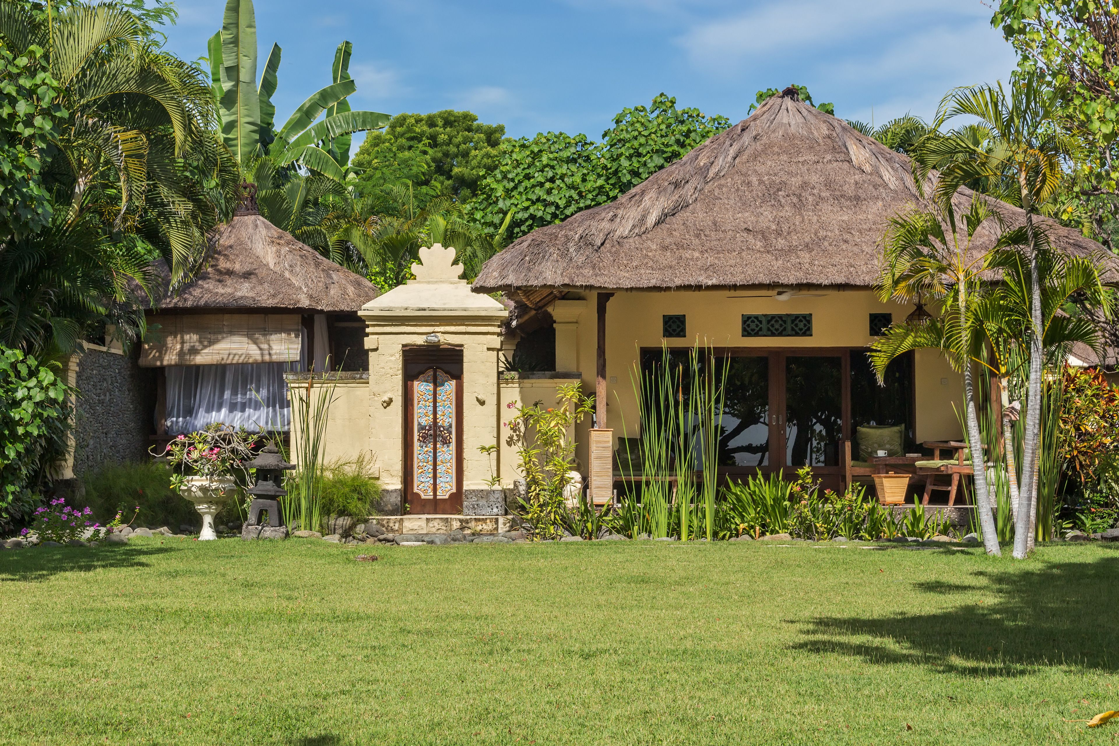 A traditional thatched-roof house with a small garden area in front.