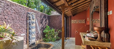 Un área de spa con pared de piedra, fuente de agua y banca de madera.
