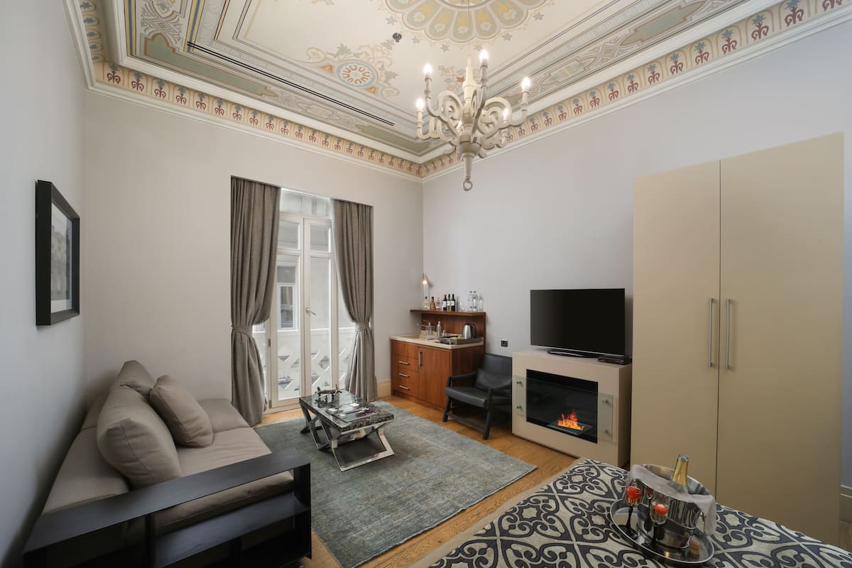 A modern living room with a sofa, a TV, a fireplace, and a minibar.