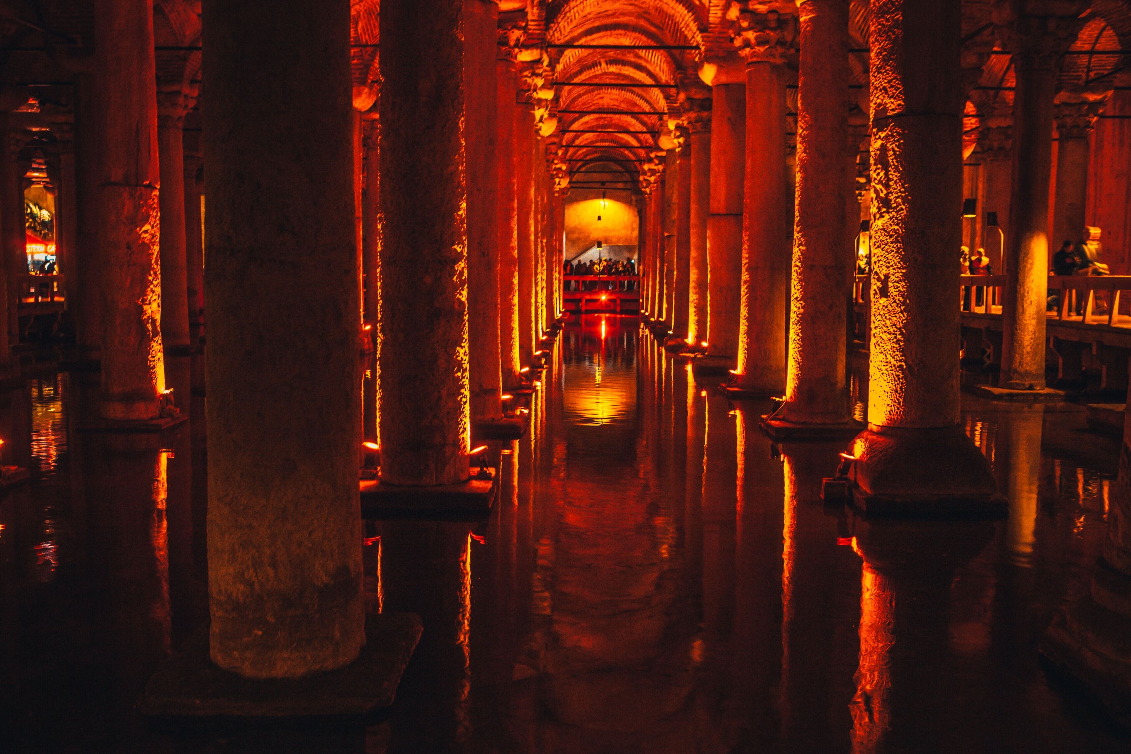 A corridor with columns and arches, leading to a central area with a reflective floor.