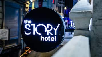 Un letrero de neón del 'The Story Hotel' en un entorno urbano.