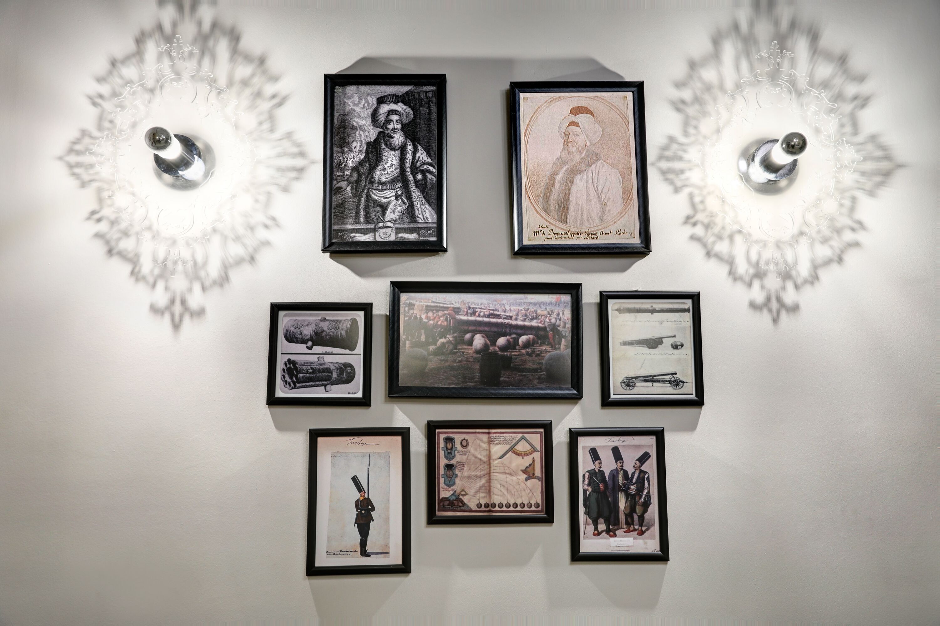 Paredes decoradas com fotografias históricas e militares emolduradas, incluindo tanques e um mapa.