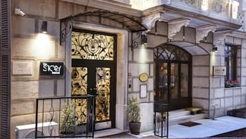Classic entrance with ornate stonework and a balcony, featuring a distinctive black and gold door.