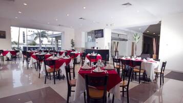 A spacious dining area with tables set for multiple guests, large windows, and a modern interior design.