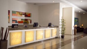 A reception desk with a modern design, a potted plant, and artwork on the wall. - Balajú Hotel & Suites (Veracruz)