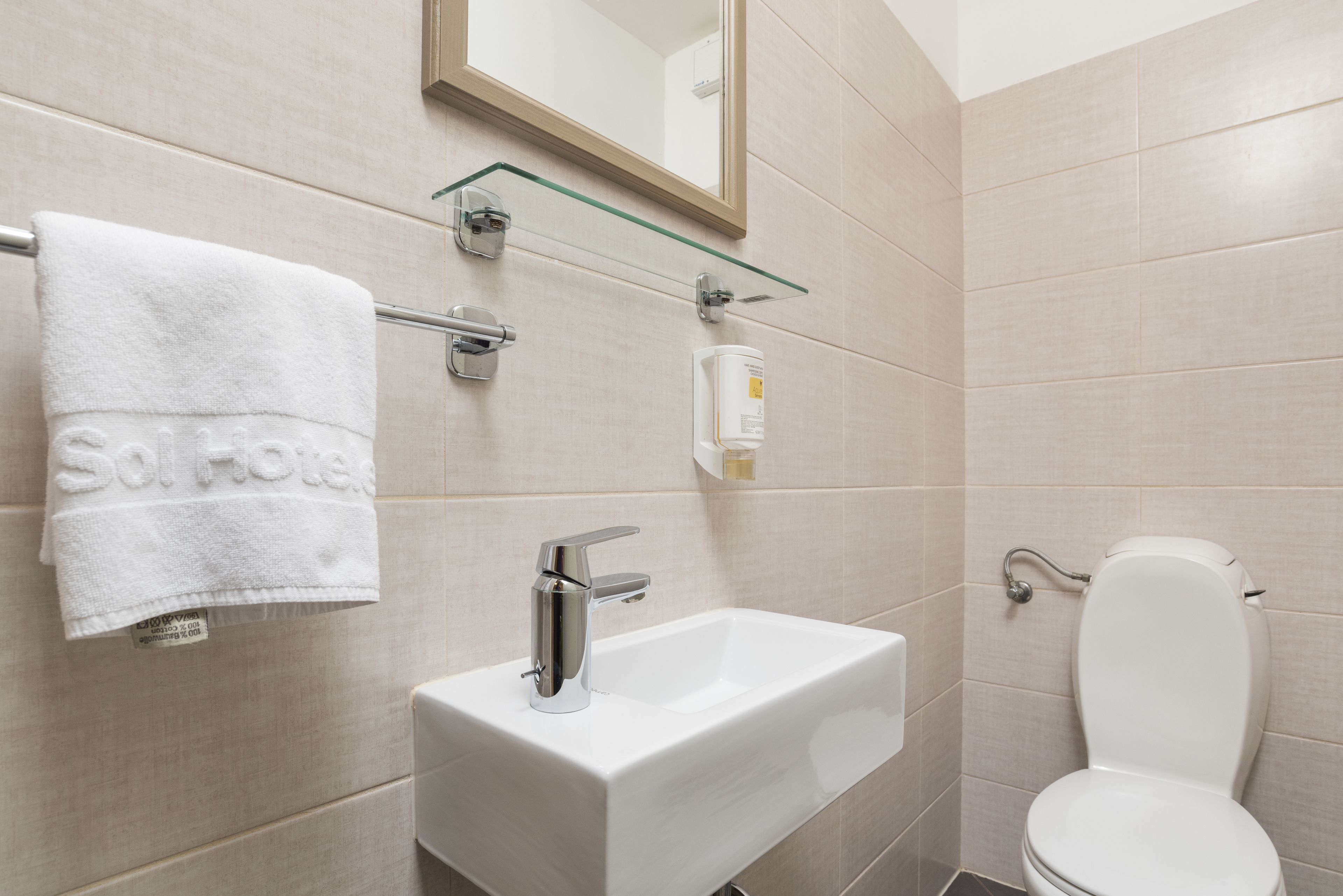 A bathroom with a white sink, a towel hanging on a rack, and a toilet.