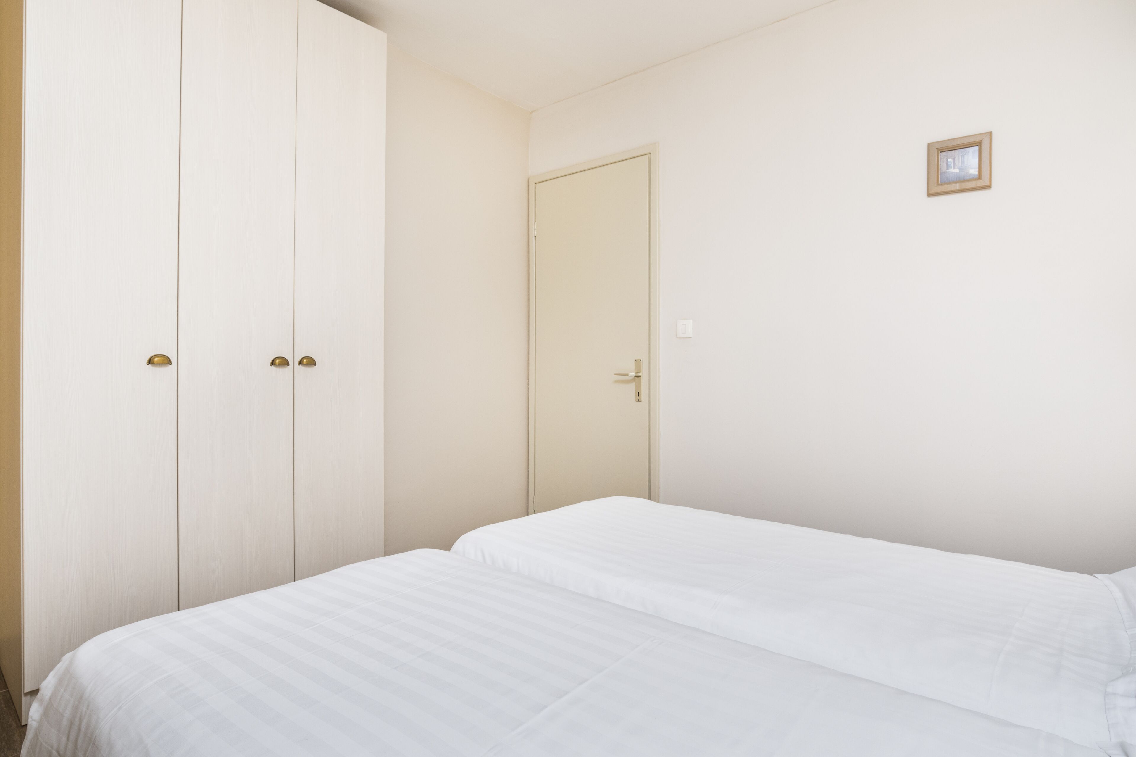 A bedroom with a bed, a wardrobe, and a door.