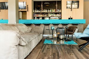 A modern living room with a sofa, a glass coffee table, and a bar area in the background.