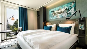 A hotel room with a large bed, a desk, and a chair. There is a painting on the wall and a window with curtains. - Motel One München-Garching (Garching)