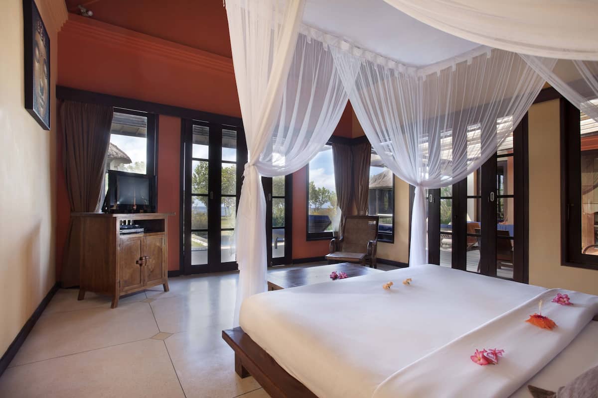 Une chambre d’hôtel avec un grand lit, une armoire en bois, une chaise et un téléviseur.