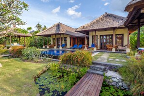 Un resort con estructuras de techo de paja, piscina y un jardín bien cuidado.
