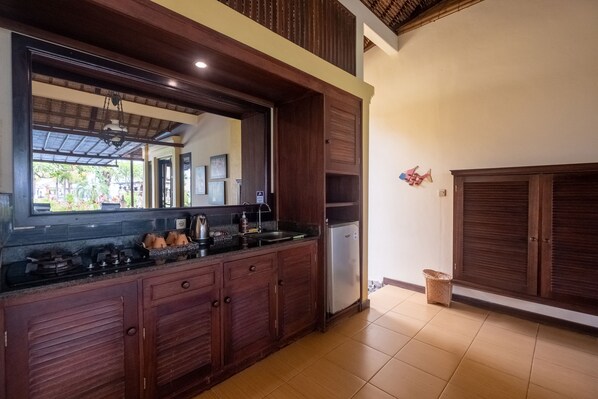 Una cocina con armarios de madera oscura, un refrigerador de acero inoxidable y un espejo grande sobre la encimera.