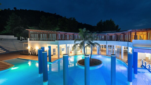 A swimming pool with a palm tree, a covered outdoor area, and a building with large windows. - Maritalia Hotel Club Village - All Inclusive (Peschici)