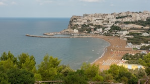 A coastal town with a beach, a pier, and buildings on a cliff overlooking the sea. - Maritalia Hotel Club Village - All Inclusive (Peschici)