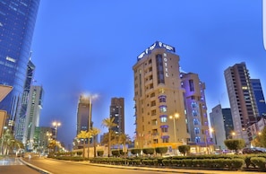 A hotel with a modern design, featuring a prominent 'HOTEL' sign on the facade. It is located in a cityscape with other high-rise buildings around.