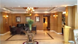 A lobby with a reception desk, a chandelier, and a decorative vase.