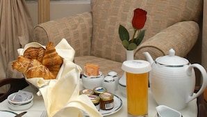 A breakfast setup with pastries, condiments, and a teapot on a table.