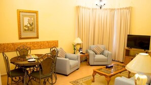 A living room with a dining table, two sofas, a TV, and a lamp.