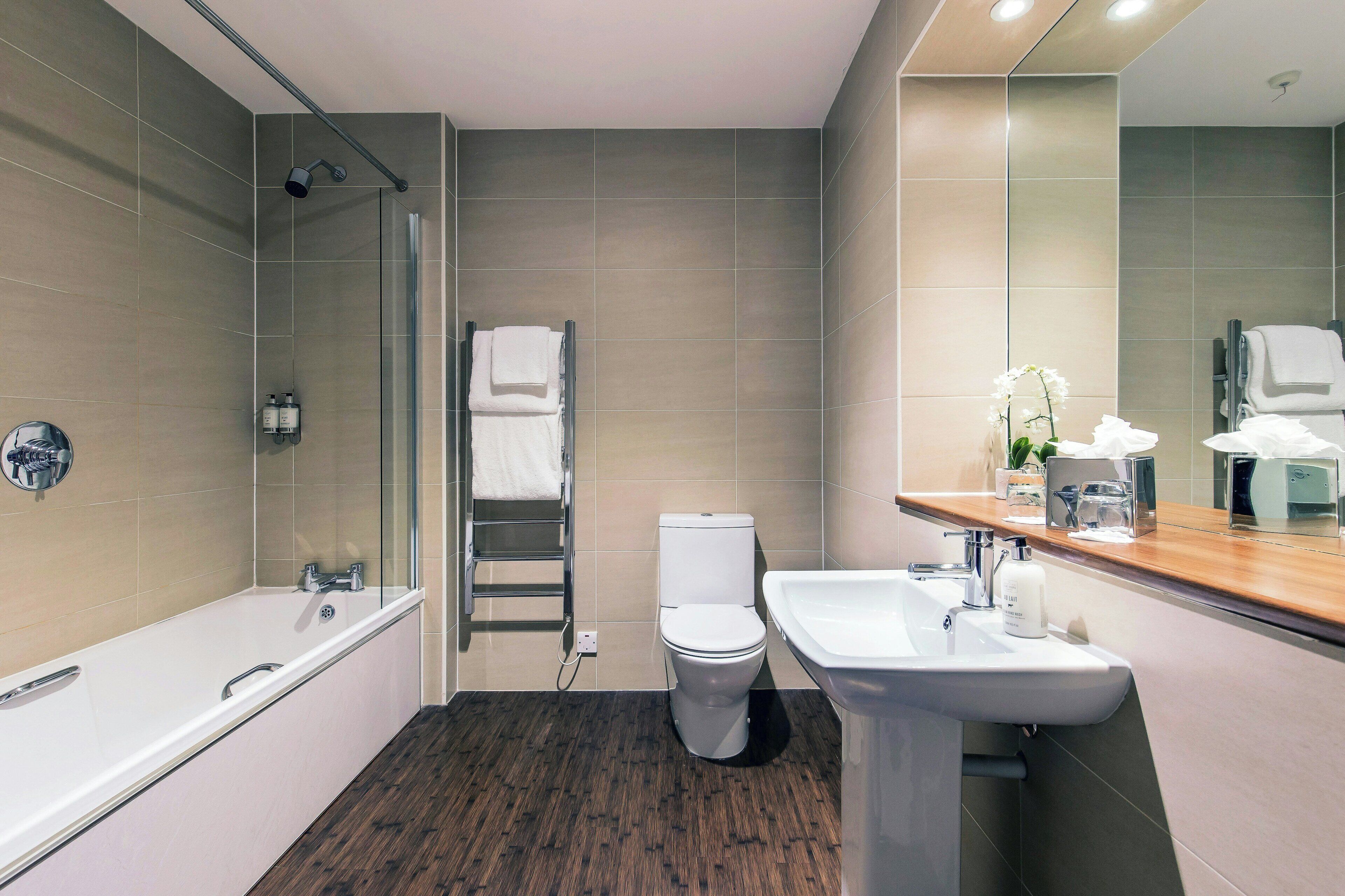 A modern bathroom with a bathtub, toilet, and sink.