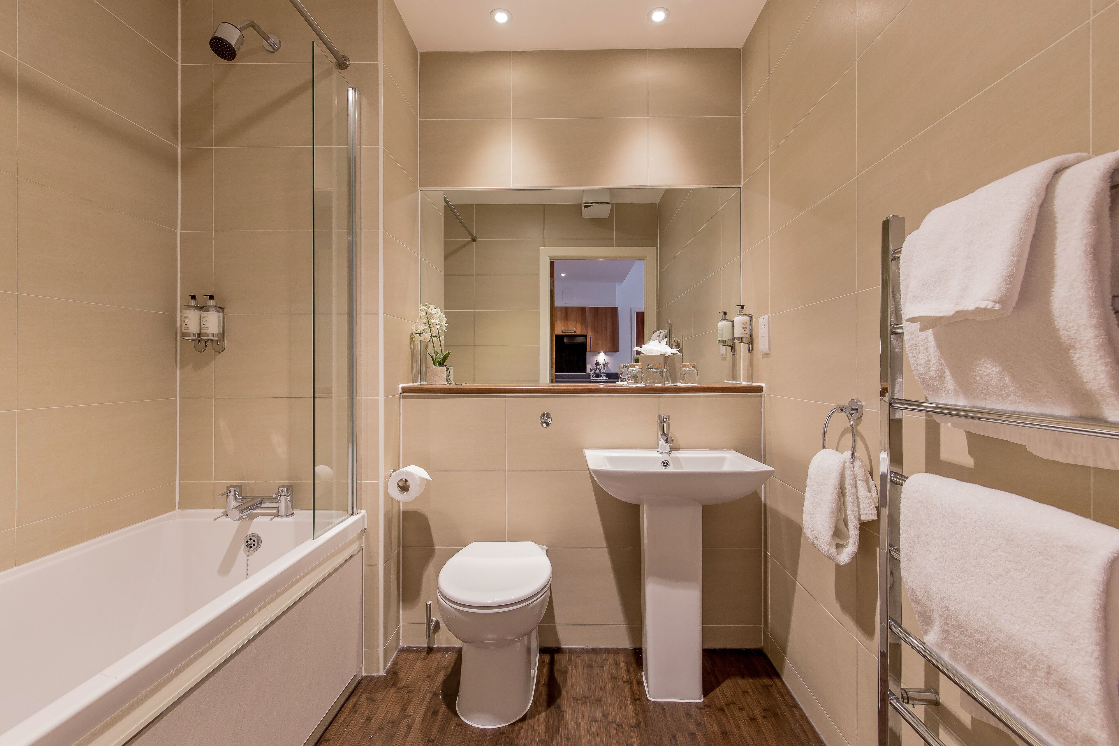 A modern bathroom with a bathtub, toilet, sink, and glass shower enclosure.