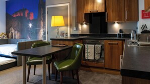 A modern kitchen with wooden cabinets, a black stove, and a dining area with a table and chairs. - Stewart by Heeton Concept (Edinburgh)