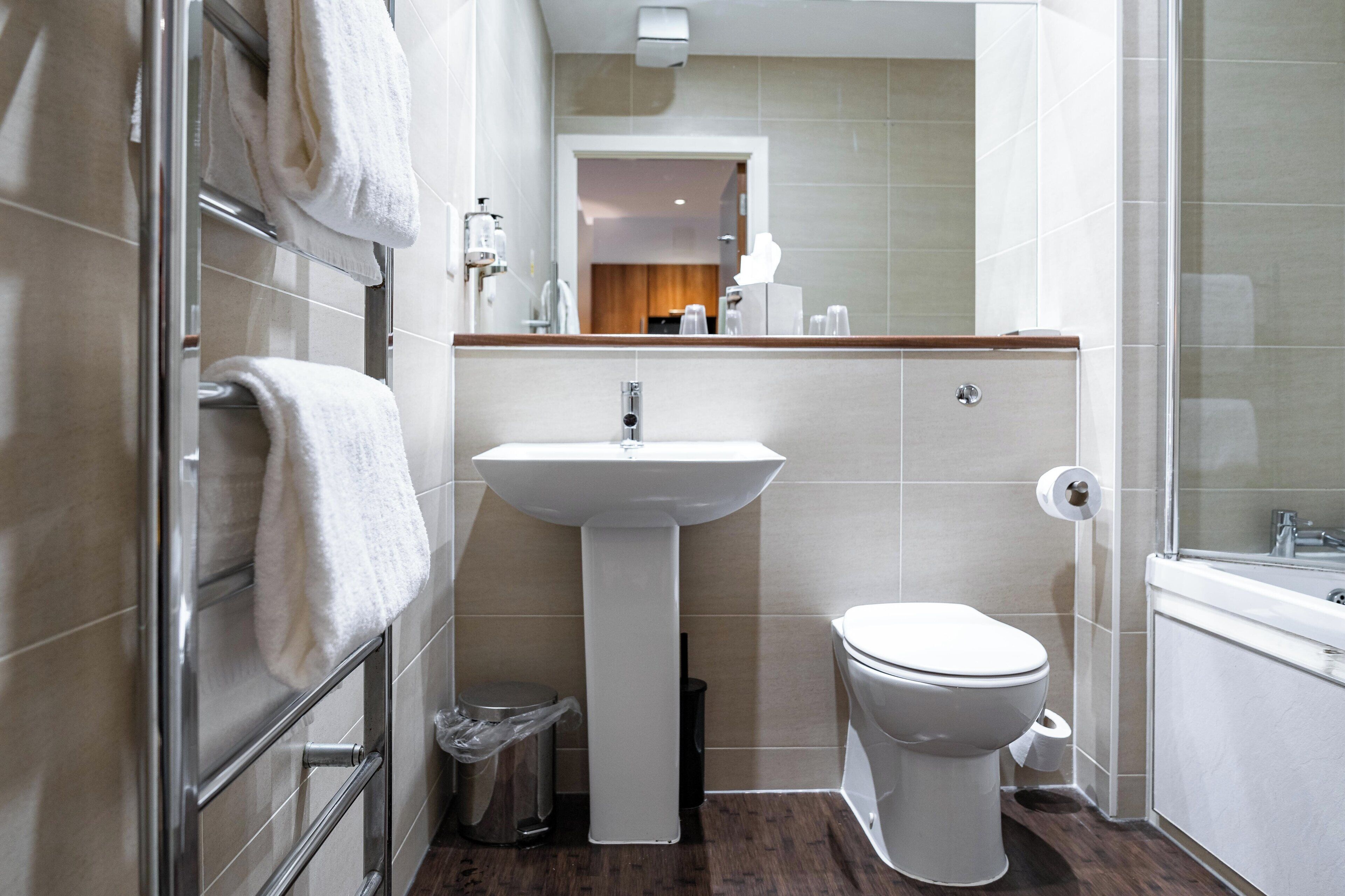 A modern bathroom with a white sink, toilet, and towel rack.
