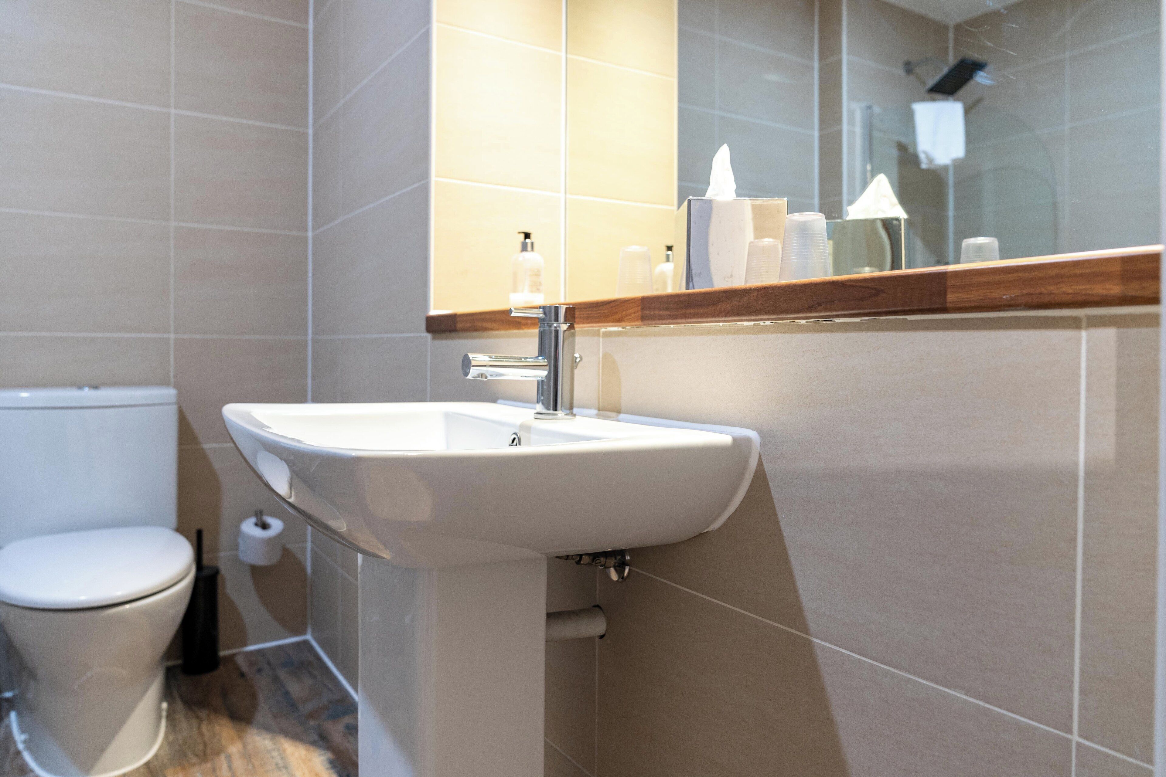 A modern bathroom with a white sink, a toilet, and a mirror above the sink.
