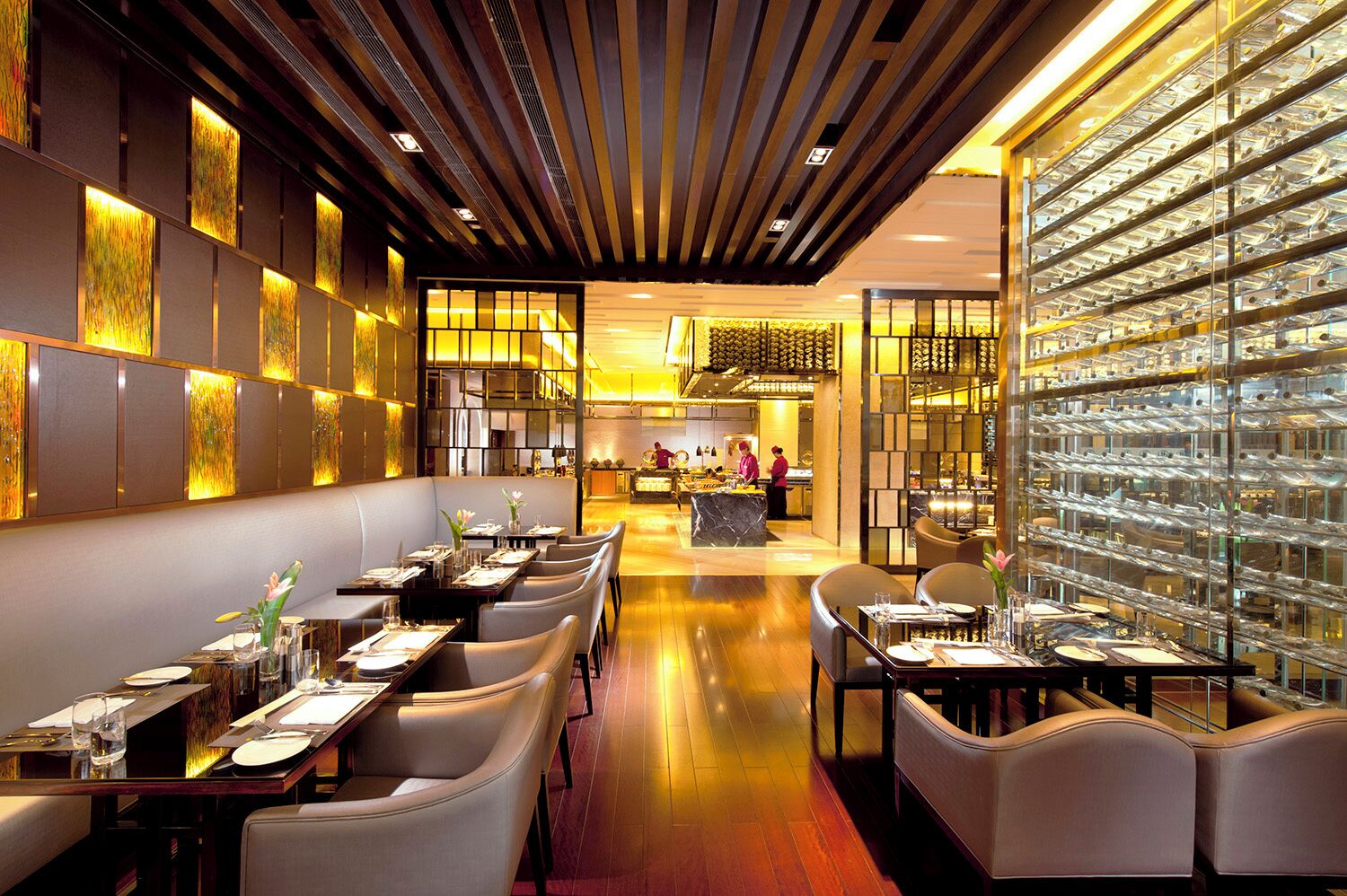 Een modern restaurantinterieur met een lange eetzône, hoge plafonds en een centrale keuken.