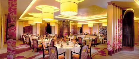 A restaurant with round tables, chairs, and a warm, yellow-lit ambiance.