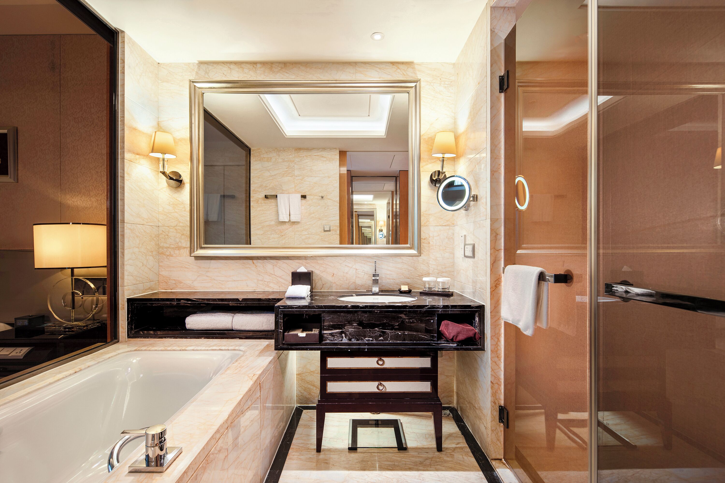 A modern bathroom with a large mirror, a bathtub, a vanity with a sink, and a shower area.