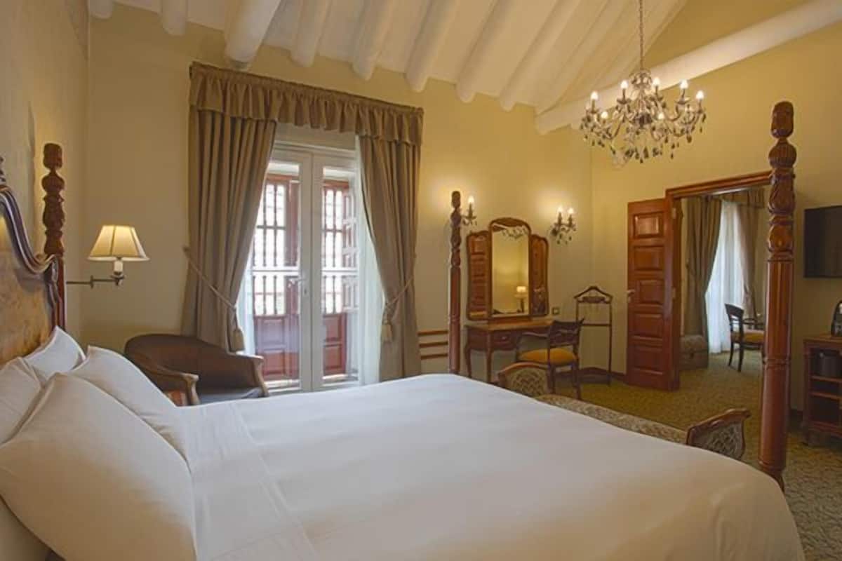 Een hotelkamer met een groot bed, een bureau, een stoel, een televisie en een kroonluchter.