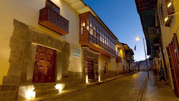 A cobblestone street with historic buildings, a wooden door, and a balcony.