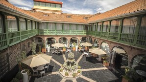 A courtyard with outdoor seating, a central fountain, and a building with a tiled roof.