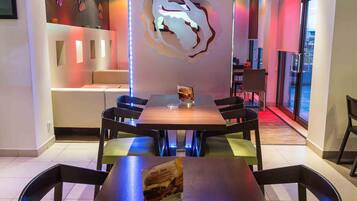 A modern dining area with a central table, chairs, and a unique wall art piece.