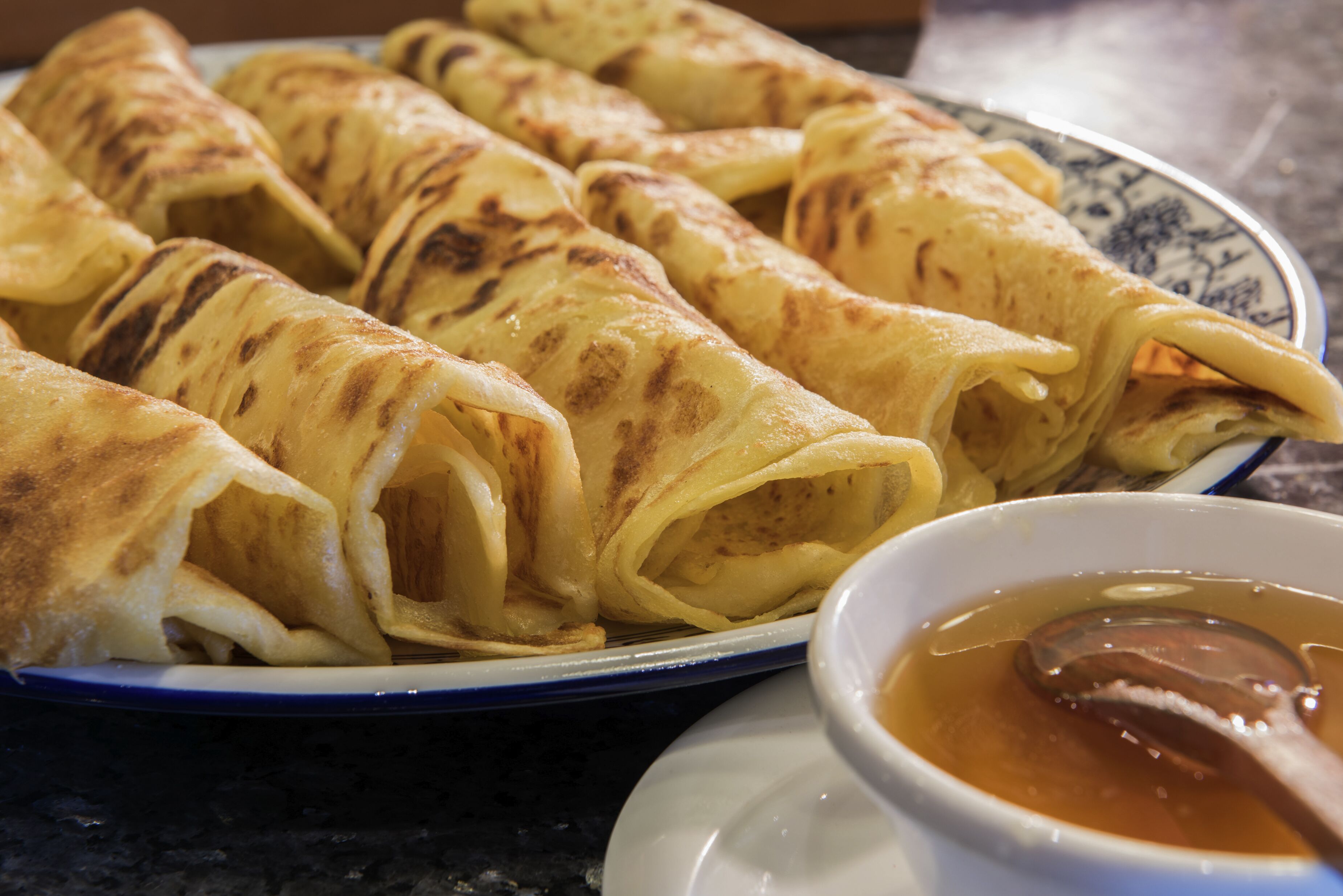 Een bord met pannenkoeken en een kom siroop.