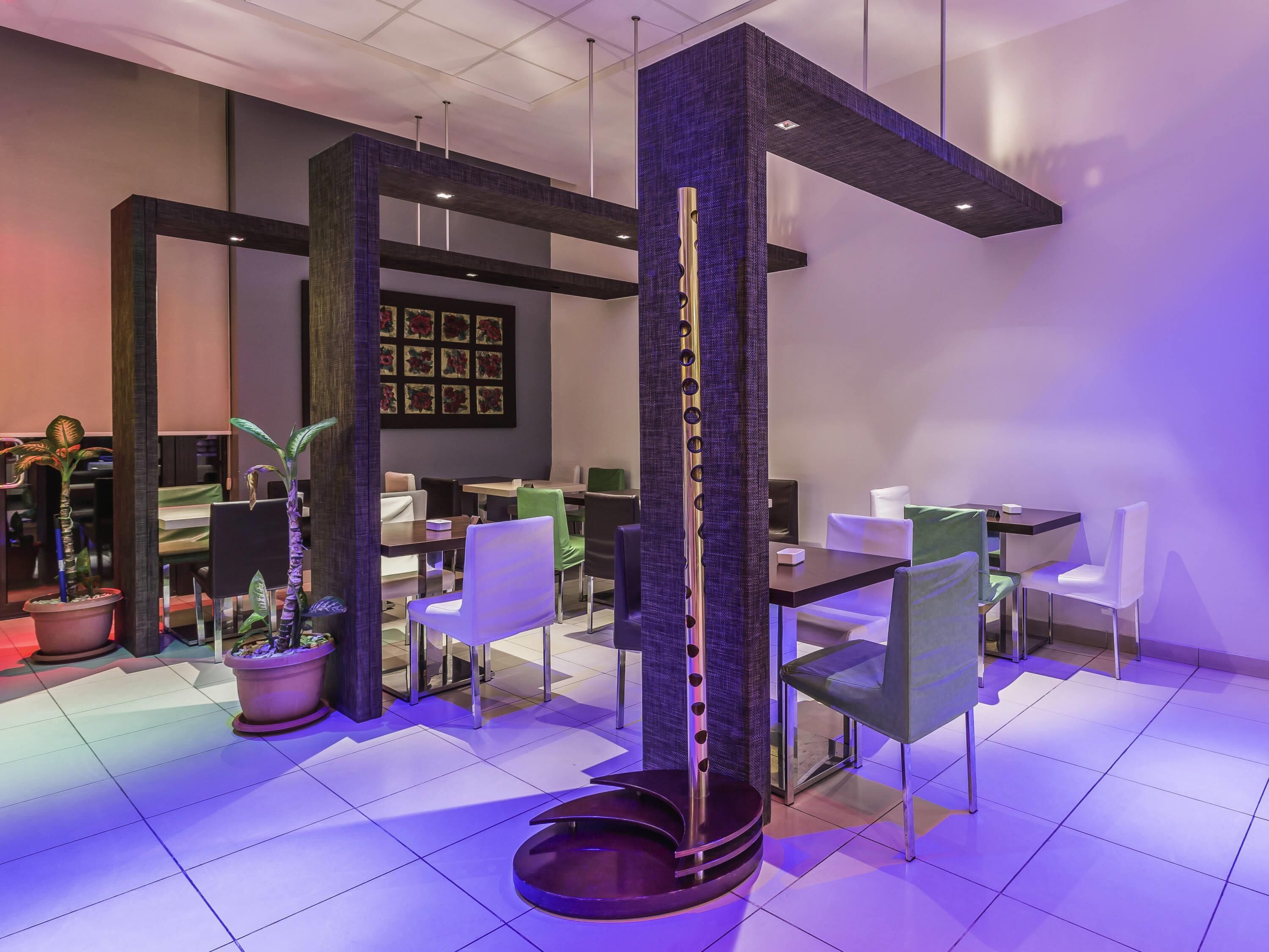 A modern interior with a central column, multiple seating areas, and a patterned wall.