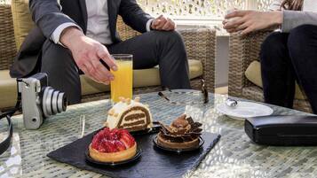 Une table avec un appareil photo, un verre de jus d’orange et trois desserts.