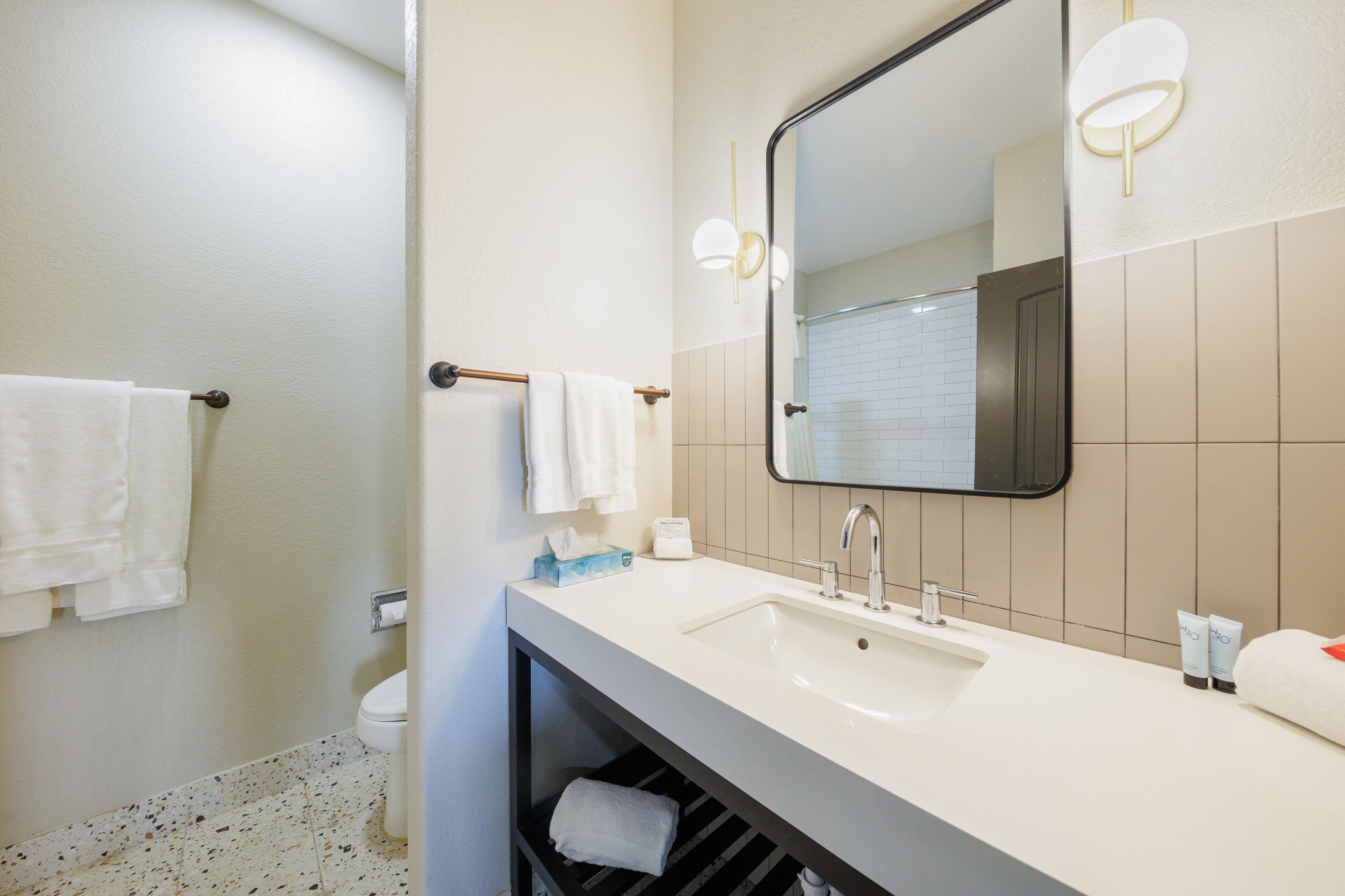 A modern bathroom with a white sink, a large mirror, and a towel rack.