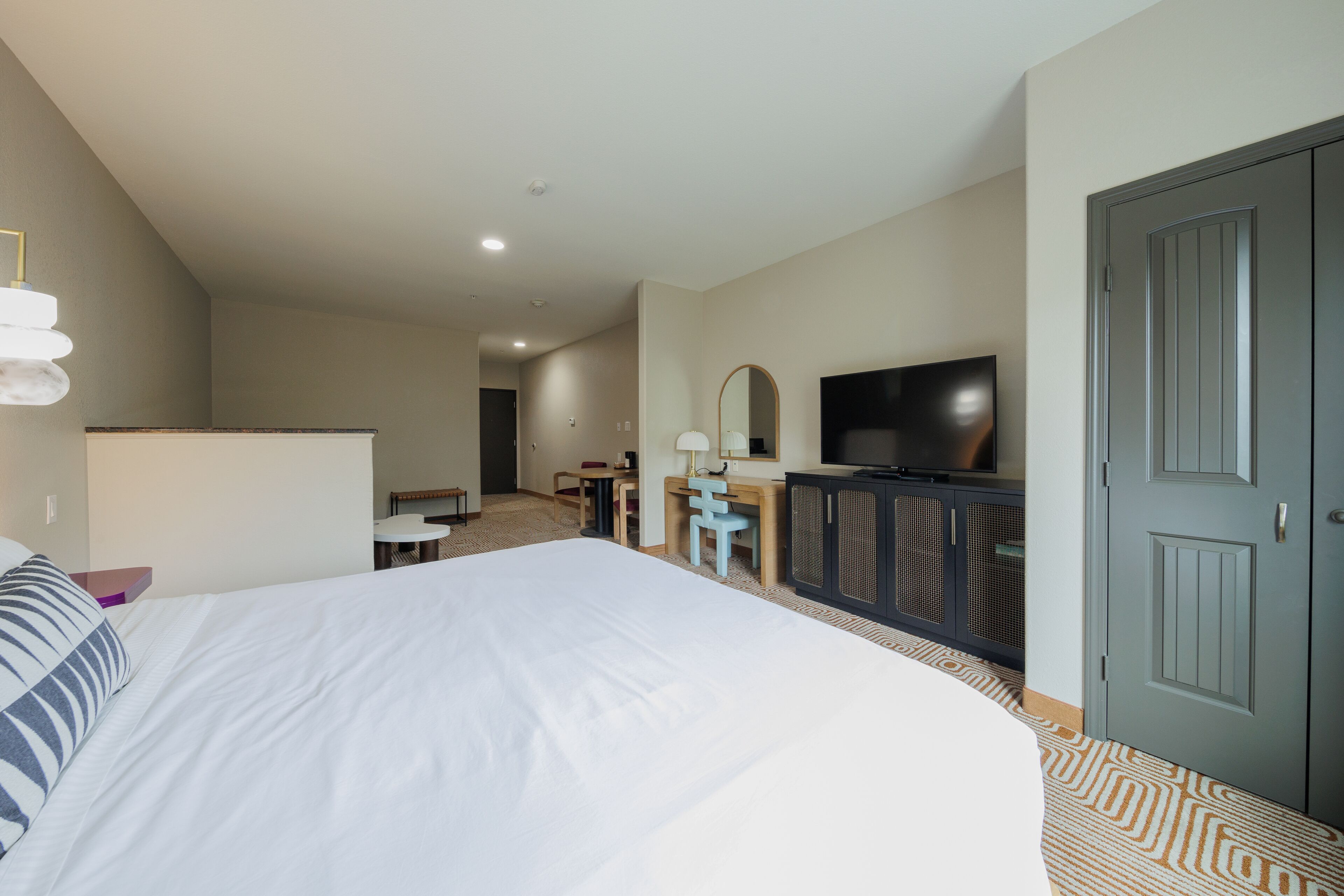A hotel room with a large bed, a desk, a television, and a wardrobe.