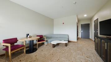 Een moderne hotelkamer met een bank, een tafeltje, een televisie en een kamerbreed tapijt met dessin.