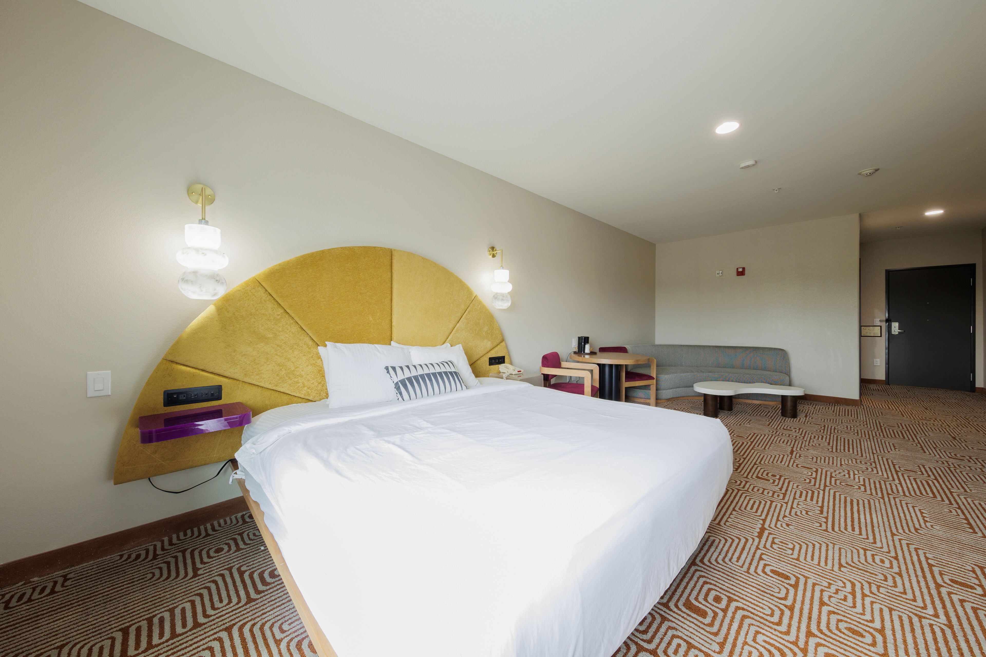 Una habitación de hotel con una cama grande, un escritorio, una silla y un sofá.